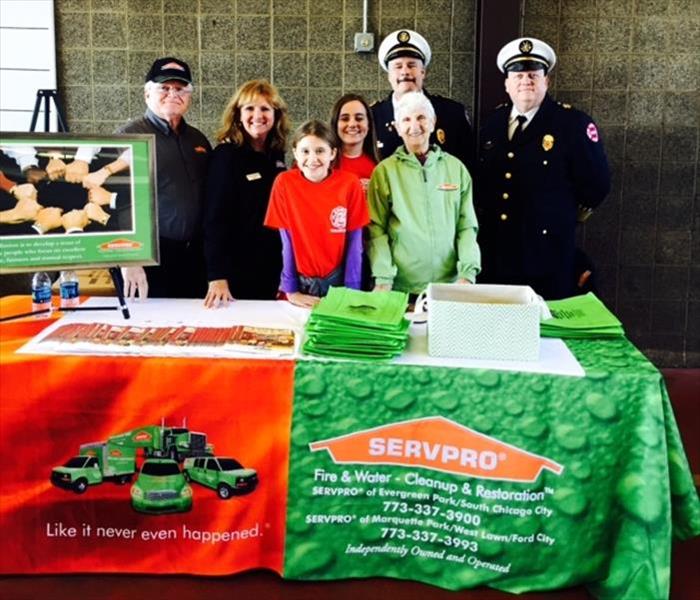 several people standing behind a table with SERVPRO promotional items