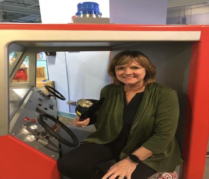 female sitting in a toy firetruck at a museum