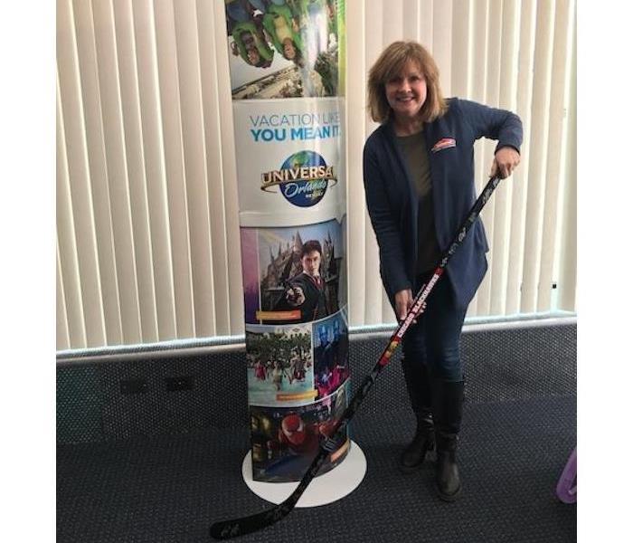 female holding a hockey stick next to a Universal Orlando sign