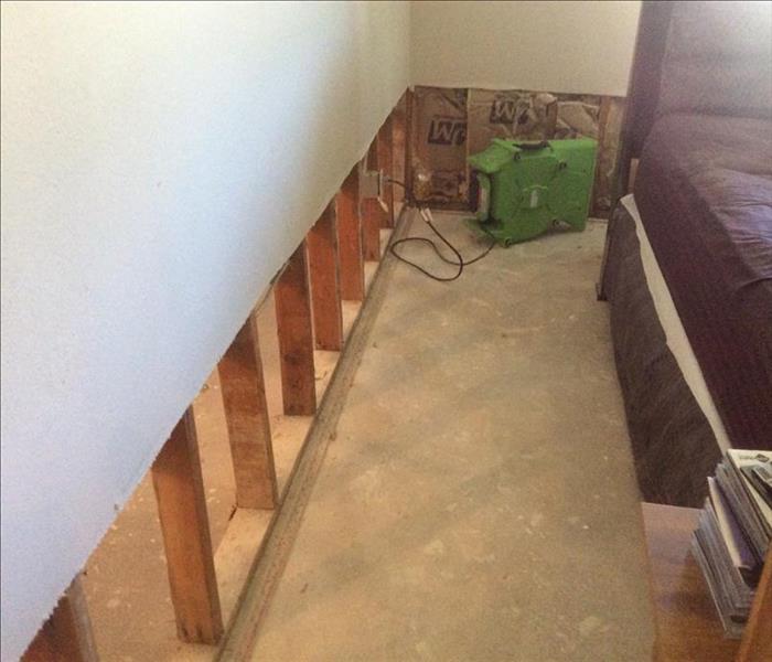hallway with exposed subfloor and drywall removed from the bottom two feet