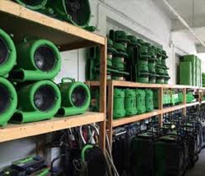 Wood shelving holding serval pieces of green SERVPRO equipment