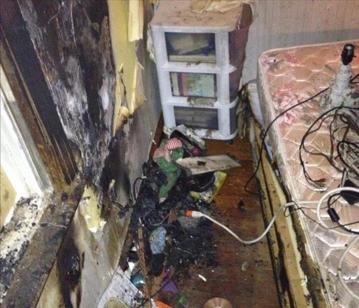 bedroom with burned and soot covering the walls and fire damaged debris on the floor