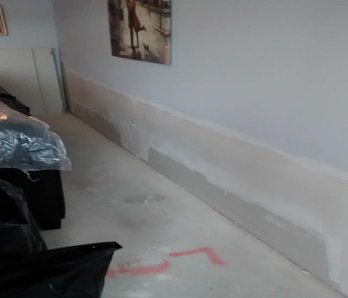 room with exposed concrete floor and new drywall installed on the bottom two feet of the wall where flood cuts were performed
