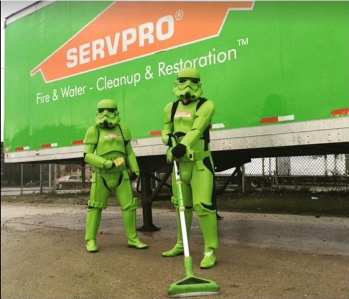 two SERVPRO techs, dressed in superhero gear, using water removal tools