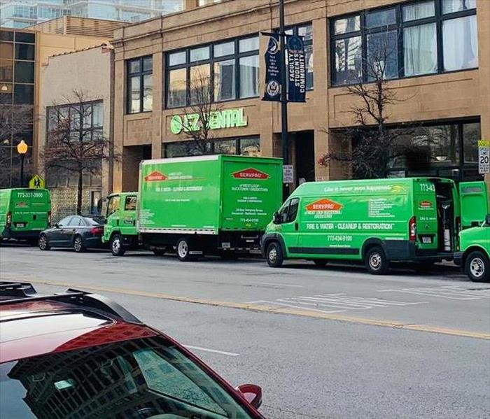 A group of SERVPRO vehicles in front of a building. 