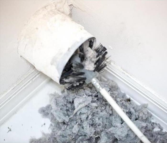 brush in a vent hole with lint on the ground