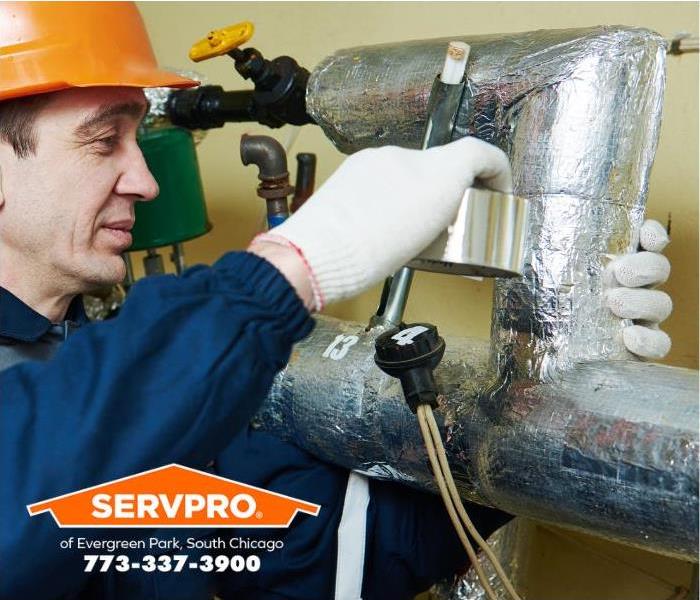 A technician wraps pipes with aluminum foil to protect them from freezing.