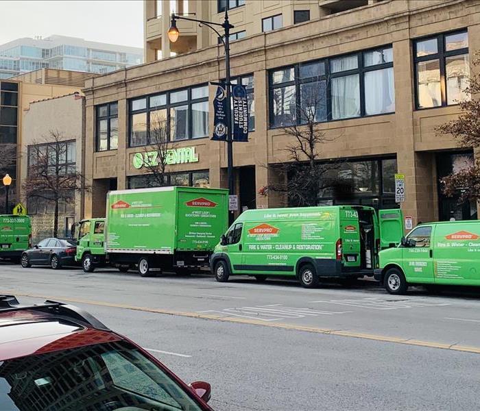 SERVPRO vans and trucks parked on the street in front of buildings