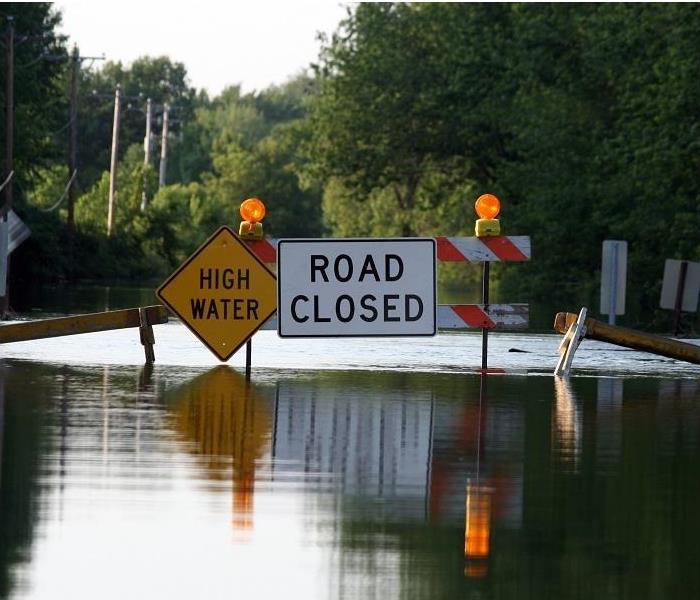 floodwater on street; 'road closed' sign
