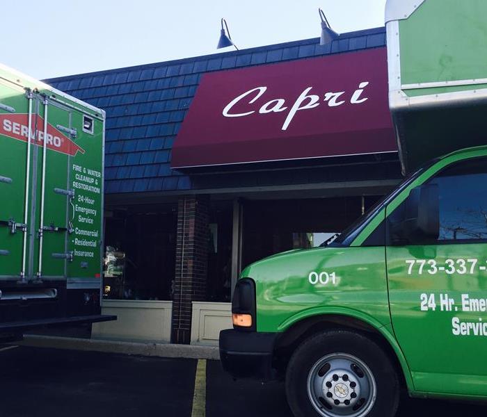 green SERVPRO trucks sitting in front of a building with Capri on the sign