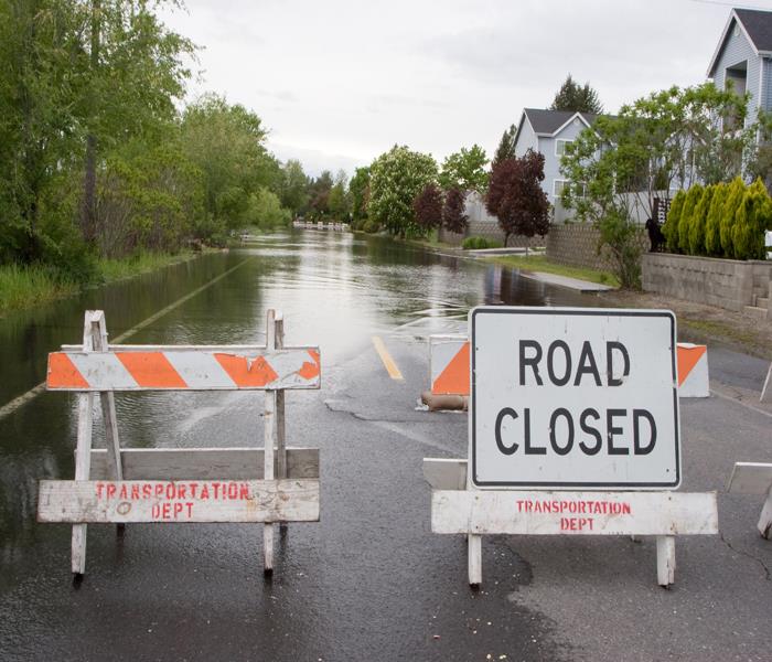 road covered in water with Road Closed signs posted